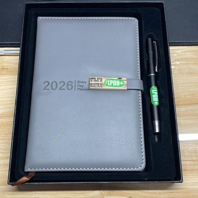 Overhead view of a branded planner and pen seated in a foam-lined presentation box.